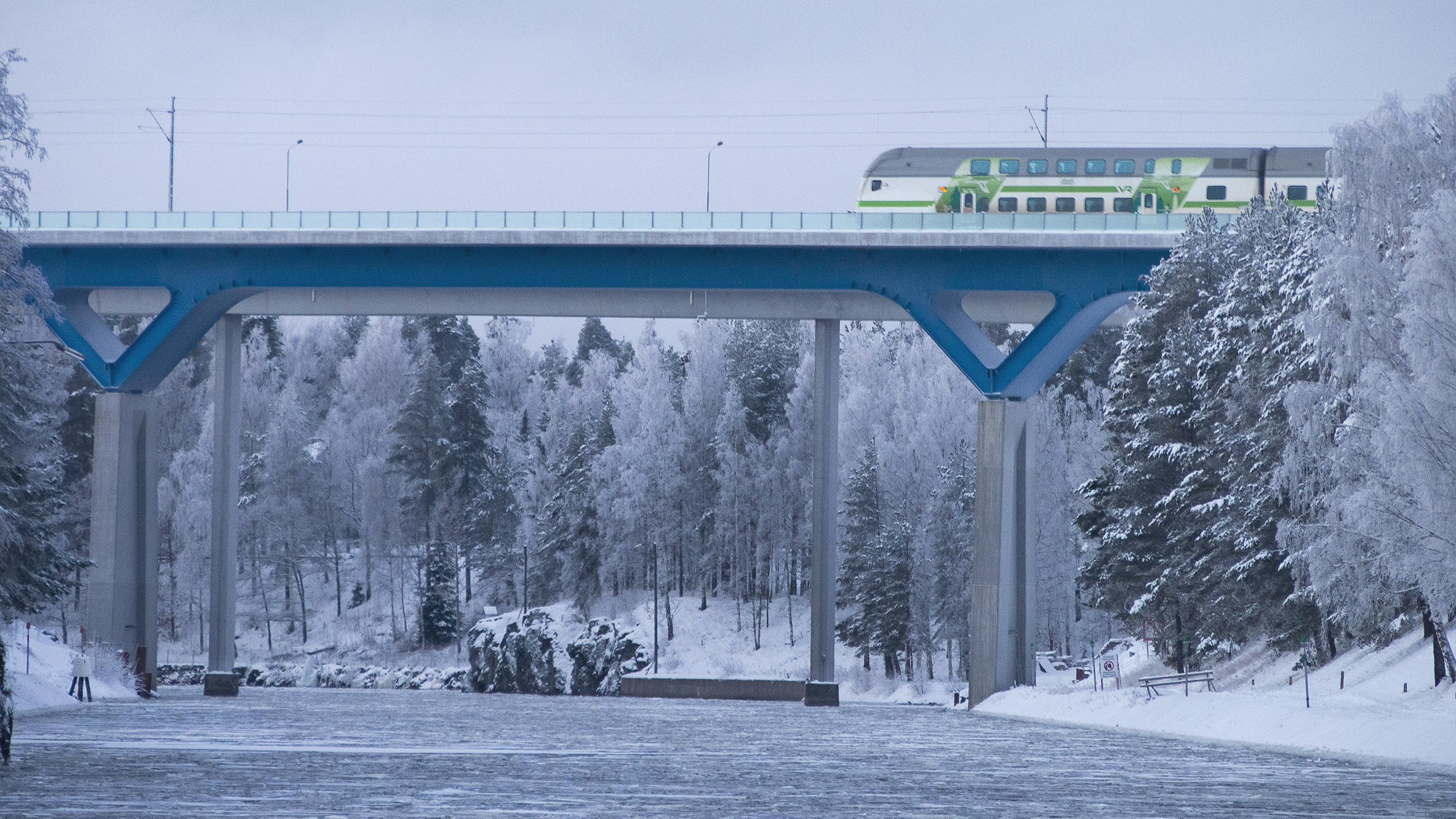 Juna ylittää kanavasillan talvisessa maisemassa.