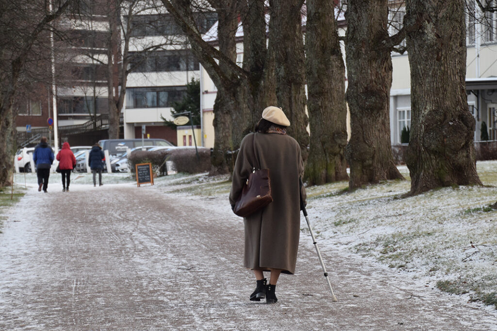 Vanhus kävelee kepin kanssa Lappeenrannan Kasinon edessä.