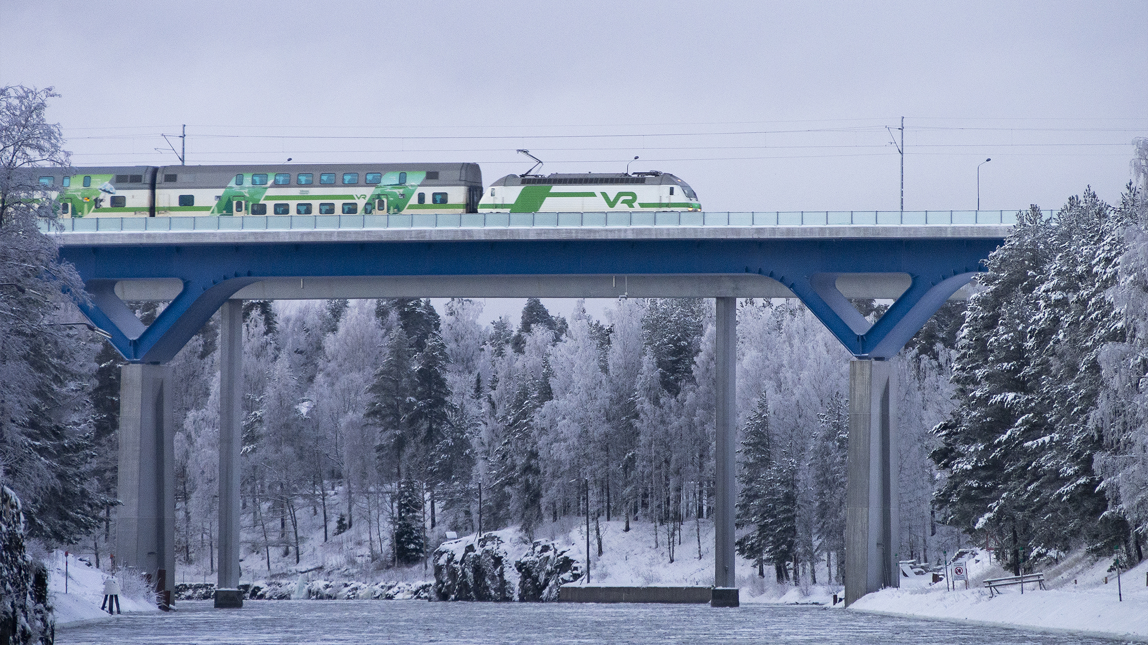 VR:n matkustajajuna kulkee Saimaan kanavan sillalla talvisessa maisemassa.