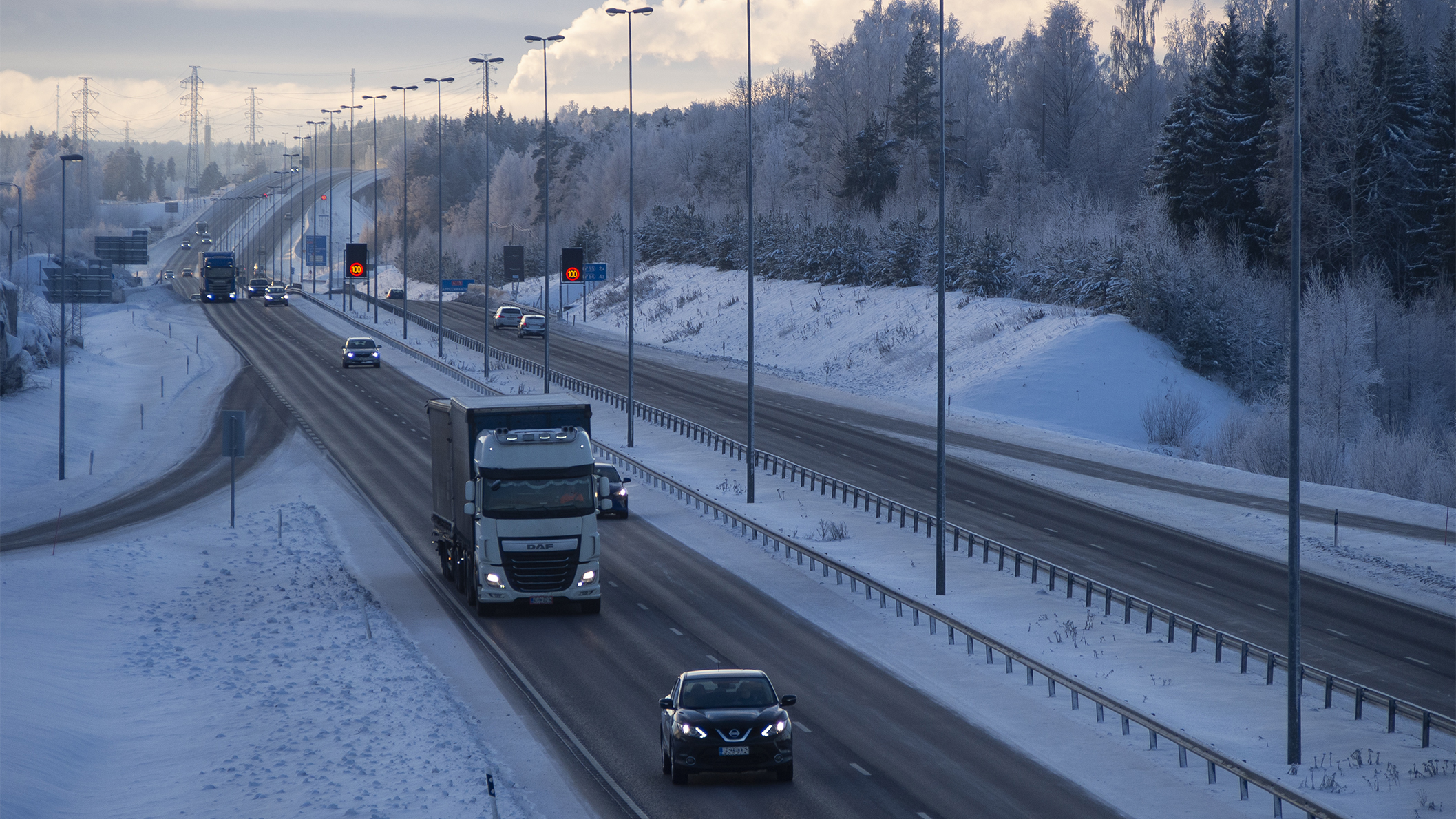 Talvinen maisema valtatie 6:sta. Tiellä liikkuu henkilöautoja sekä kuorma-autoja.