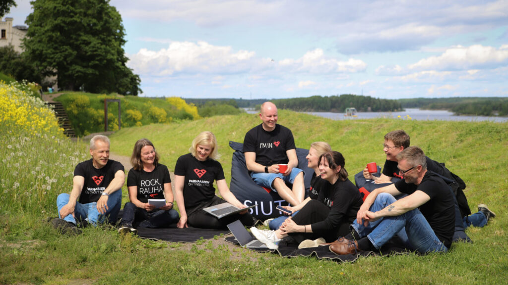 Etelä-Karjalan liiton työntekijöitä istuu nurmikolla.