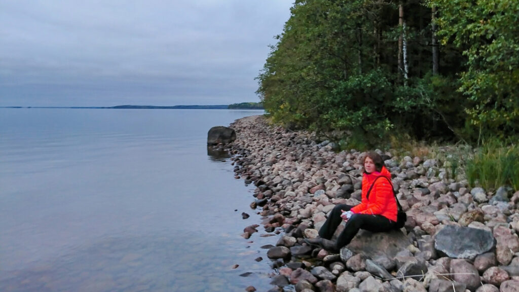 Ympäristöasiantuntija Laura Blomqvist istuu Saimaan rannalla.
